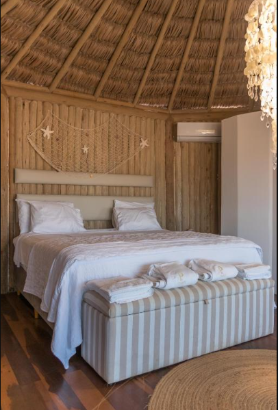 Quarto do bangalô com paredes de bambu e cama de lençóis brancos
