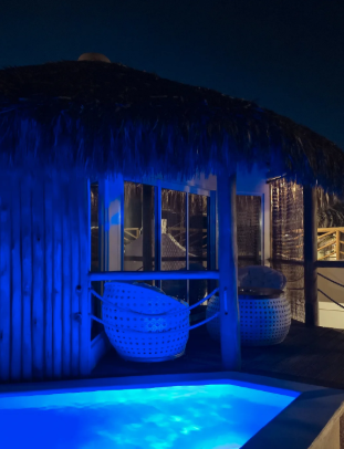 Bangalô do Positano Village iluminado em azul à noite, com piscina privativa
