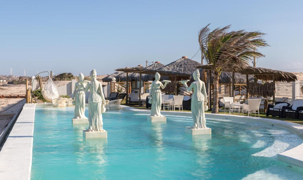 Piscina com esculturas brancas e a praia ao fundo