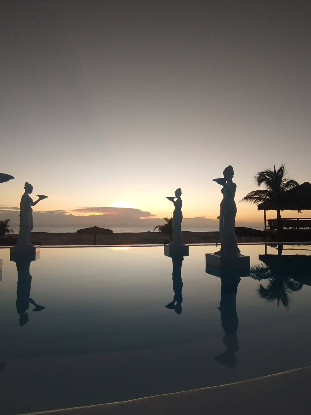 Pôr do sol na piscina do Positano Village com as esculturas em silhueta
